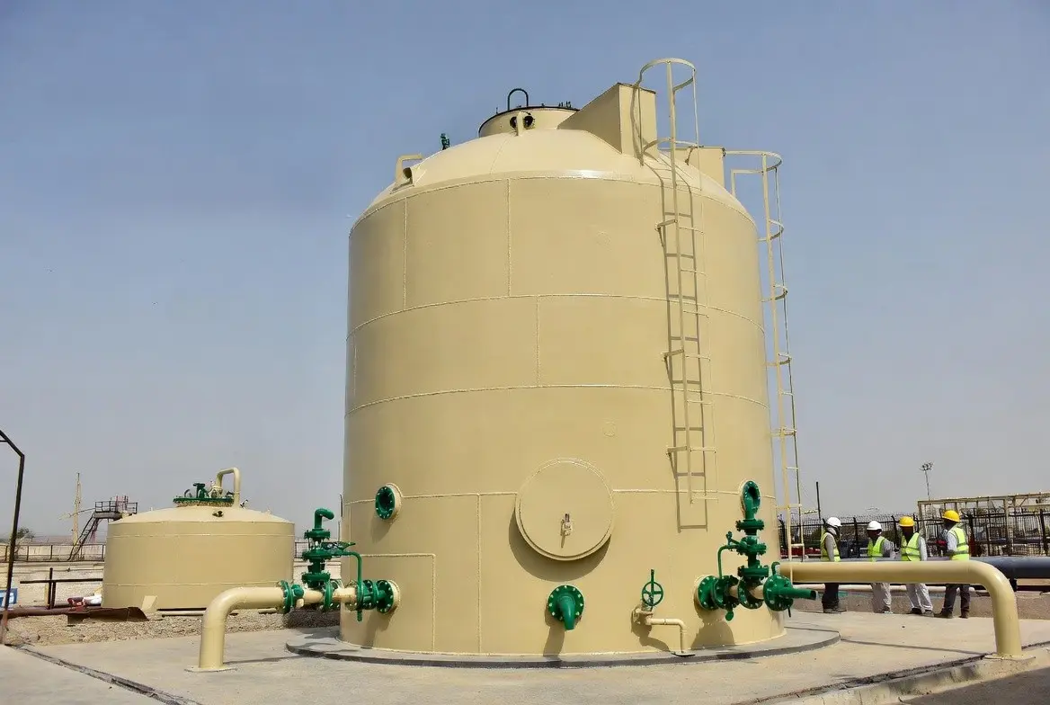 Large-scale vertical GRP industrial storage tank with connected piping system at an industrial site by Global Fiberglass Company.