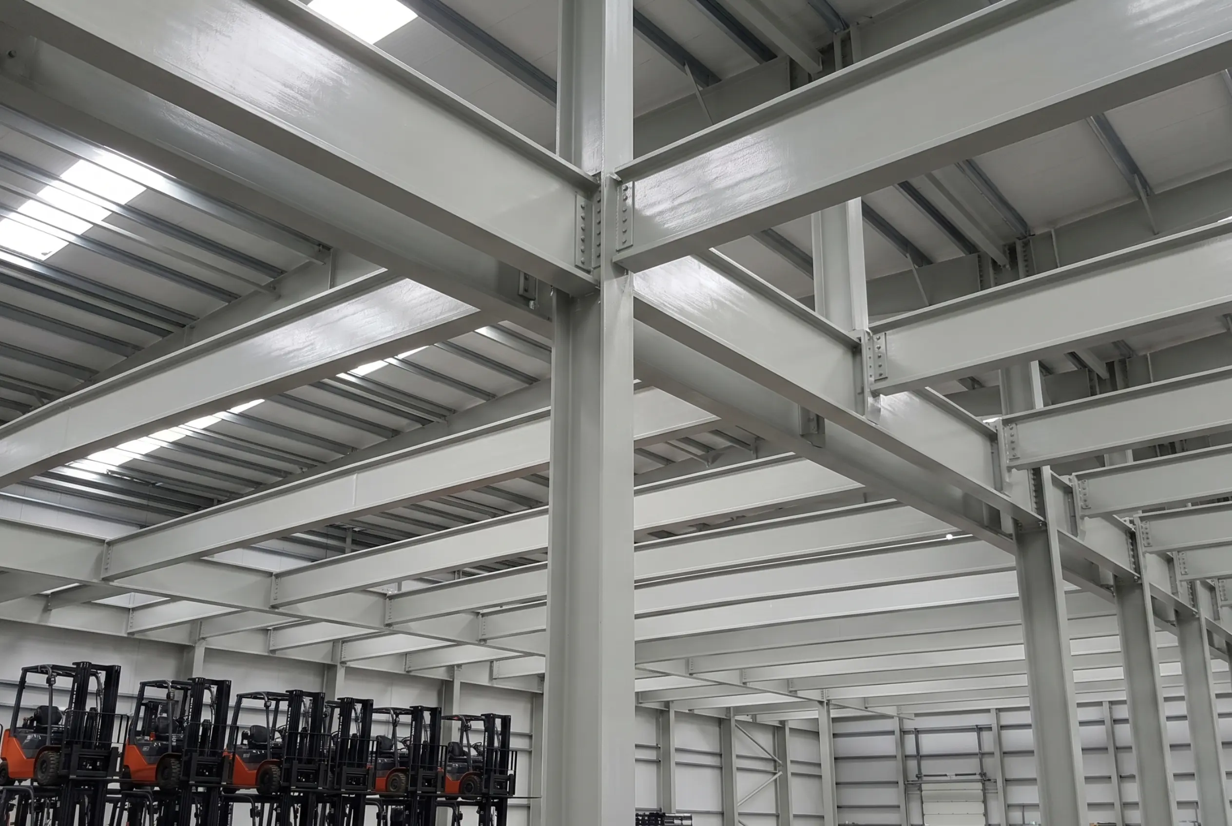Interior view of a warehouse construction project using grey FRP structural I-beams and columns as a lightweight alternative to traditional steel framing.
