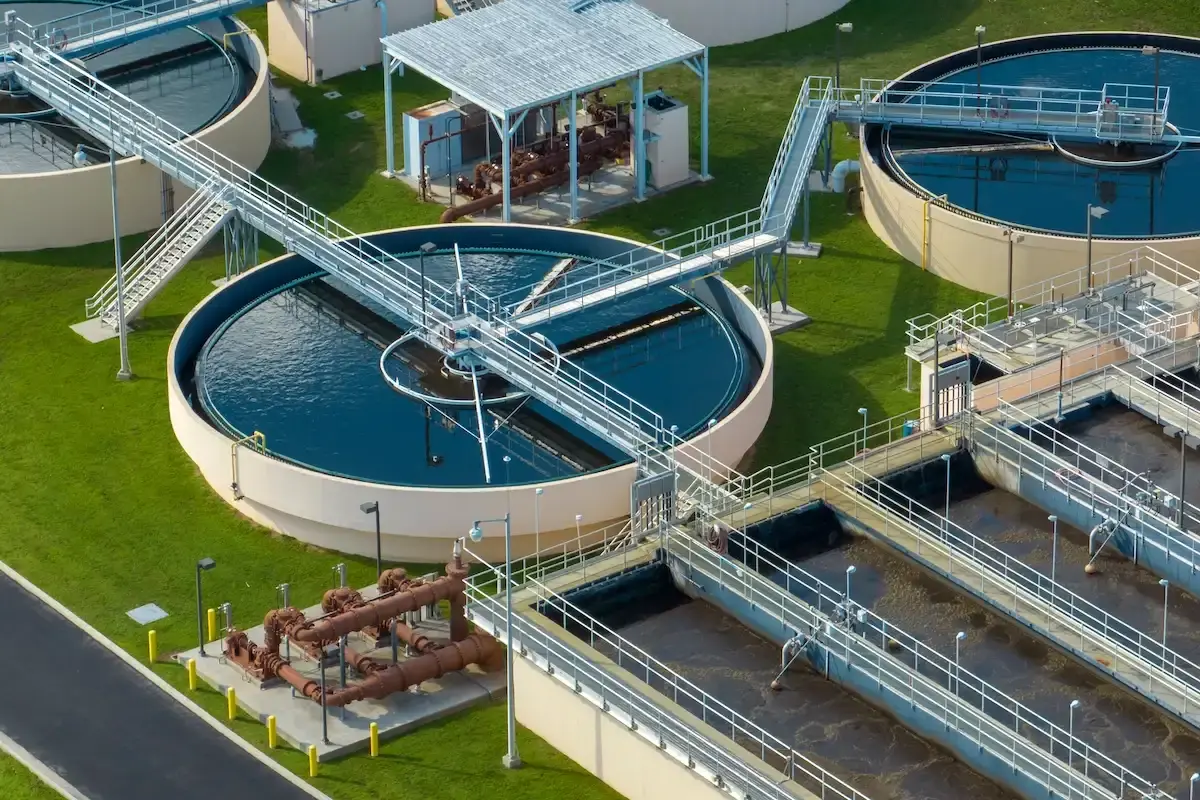 Aerial view of industrial wastewater treatment facility featuring large circular GRP/FRP settling and filtration tanks.