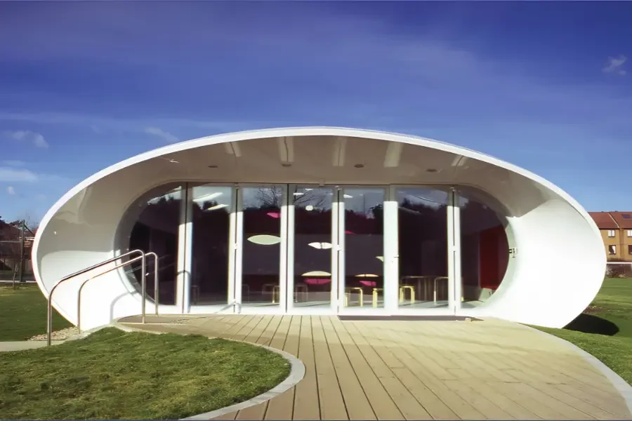 GRP material se bani hui ek modern, curved shape ki modular building, jo lightweight strength aur architectural design flexibility ko dikhati hai.